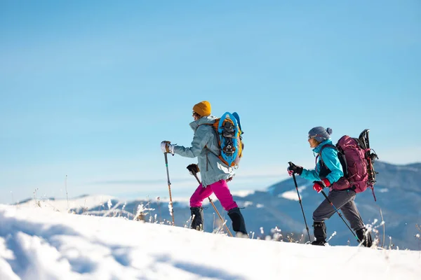 两名妇女在雪地里走着过冬 两名妇女在山里走着过冬 带着远足装备和雪鞋 — 图库照片