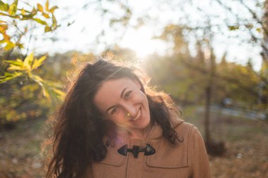 Sonbahar yürüyüşü sırasında siyah saçlı güzel bir kızın portresi. Kız kameraya gülümsüyor.