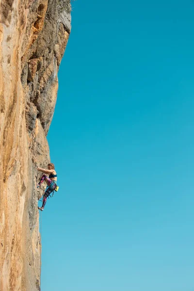 女性は青い空に対して岩を登る 強い女の子は強さと持久力を訓練 極端なスポーツ 自然の地形にロッククライミング ロッククライマーはロープで登る — ストック写真