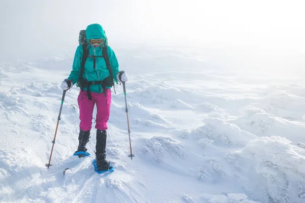 一个女人在冬天的大雾中穿雪鞋走路 一个人在冬天的山上 徒步旅行的设备 暴风雪 — 图库照片