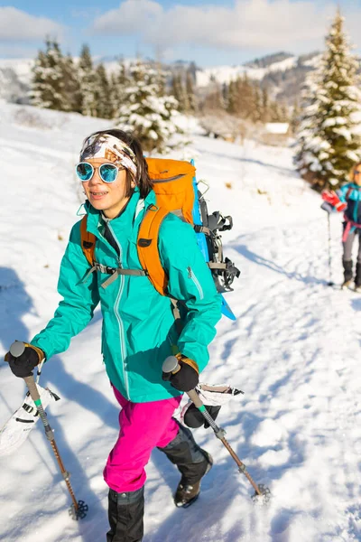 Two women walk with snowshoes on the backpacks, winter trekking, two people in the mountains in winter, hiking equipment