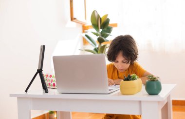 Çocuk evde video öğretmeniyle, evde, evde, uzaktan öğrenme, çevrimiçi eğitim, çevrimiçi ders alan çocuk, uzaklık eğitimi ve internet üzerinden öğrenim görüyor.