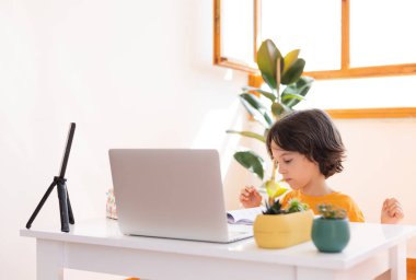 Çocuk evde video öğretmeniyle, evde, evde, uzaktan öğrenme, çevrimiçi eğitim, çevrimiçi ders alan çocuk, uzaklık eğitimi ve internet üzerinden öğrenim görüyor.