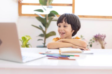 Online distance learning. a boy with a computer communicate via videoconference with a teacher and a class group. The child communicates online.