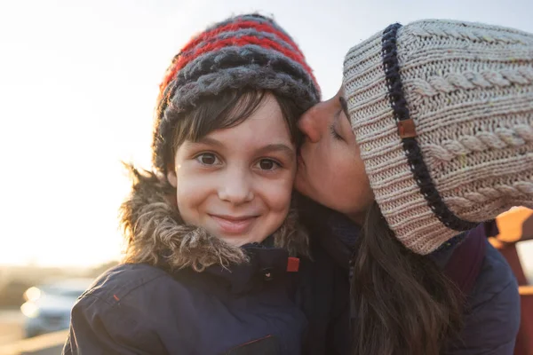 mom kisses happy son. portrait of a child and mom in winter clothes