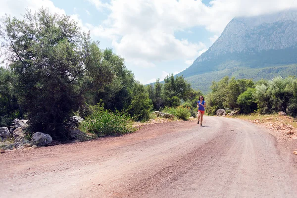A girl runs along a mountain trail, a woman runs in the mountains, outdoor sports, an active lifestyle