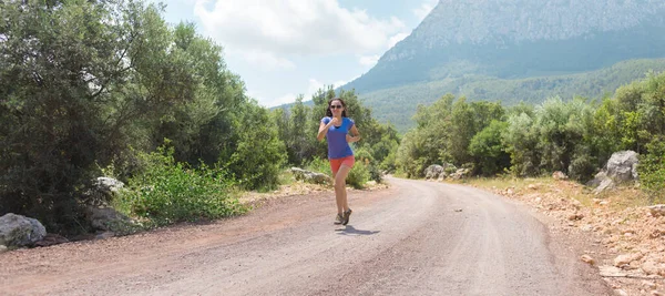 Bir kız dağ yolunda koşuyor, bir kadın dağlarda koşuyor, açık hava sporları, aktif bir yaşam tarzı.