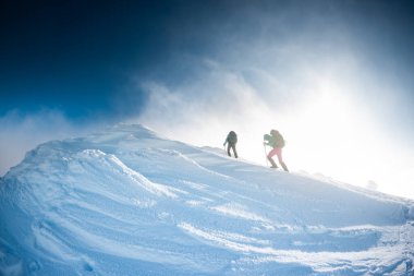 climbers climb the mountain. two girls in snowshoes walk in the snow. hiking in the mountains in winter.