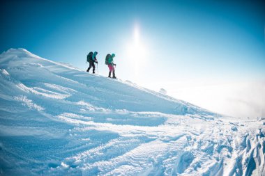 two girls walk along a mountain path in snowshoes. walking in the snow. hiking in the mountains in winter.
