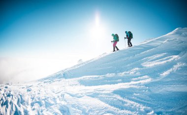 two girls walk along a mountain path in snowshoes. walking in the snow. hiking in the mountains in winter.