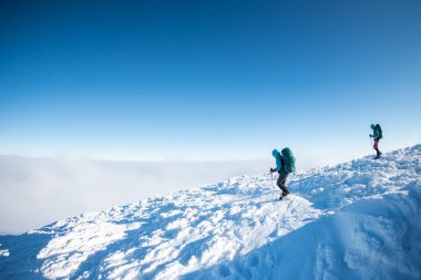 Sırt çantalı iki kadın karda kar ayakkabılarıyla, kış yürüyüşü, kışın dağlarda iki kişi, yürüyüş ekipmanları.