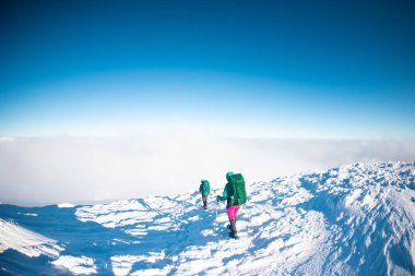Sırt çantalı iki kadın karda kar ayakkabılarıyla, kış yürüyüşü, kışın dağlarda iki kişi, yürüyüş ekipmanları.