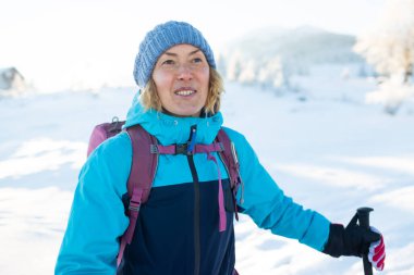 Kış yürüyüşünde sırt çantalı bir kadın, kış yürüyüşü, kar kaplı dağların arka planında bir kız.