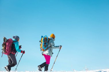 two girls walk along a mountain path in snowshoes. walking in the snow. hiking in the mountains in winter.