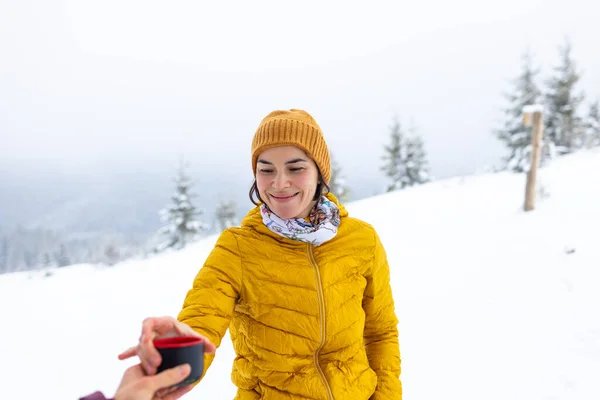 woman is drinking hot drink during winter trekking, winter camping in mountains