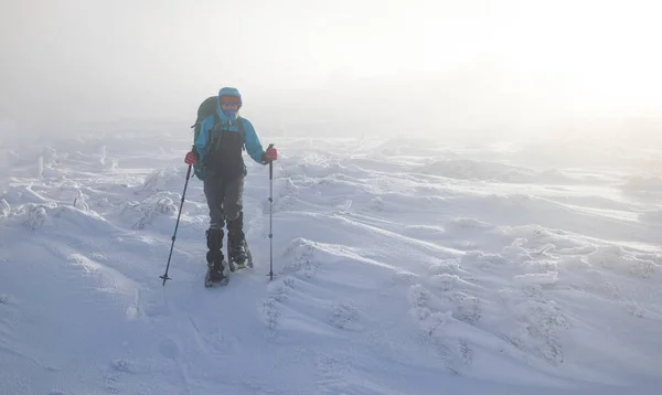 一个女人在冬天的大雾中穿雪鞋走路 一个人在冬天的山上 徒步旅行的设备 暴风雪 — 图库照片
