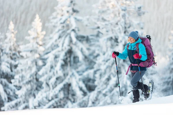 一个女人穿着雪鞋在雪地里行走 一个人在冬天徒步旅行 一个人在山上爬山 带着登山装备 — 图库照片