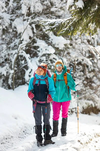 Δύο Κορίτσια Σακίδια Περπατούν Μέσα Στο Χιόνι Ανάμεσα Στα Δέντρα — Φωτογραφία Αρχείου