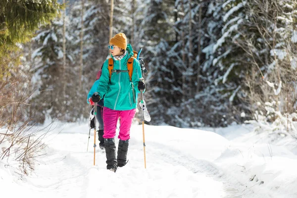 两个背着背包的女孩走在树林里的雪地里 冬天在山上徒步旅行 在山上探险 — 图库照片