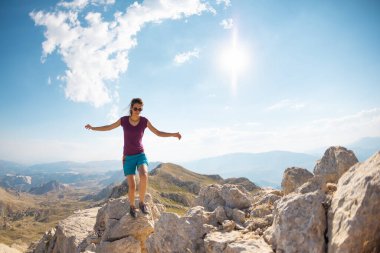 a girl walks along the ridge of a mountain against the background of the sky and mountains. mountain run. travel and adventure.