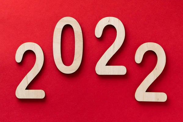 2022 рік дерев'яні номери лежать на фоні червоного паперу з тінями — стокове фото