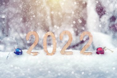 2022 yılbaşı kontrplak rakamları, kış ormanlarında kar yığınları, kar taneleri ve güneş ışınları olan bir kar yığınında. Yüzeyin derinliği. Mutlu yıllar 2022