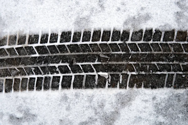 Above view of a car tire track on the snow covering the asphalt on the street close up — Stock fotografie