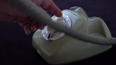 Mans eski bir döner telefondan bir numara çeviriyor.