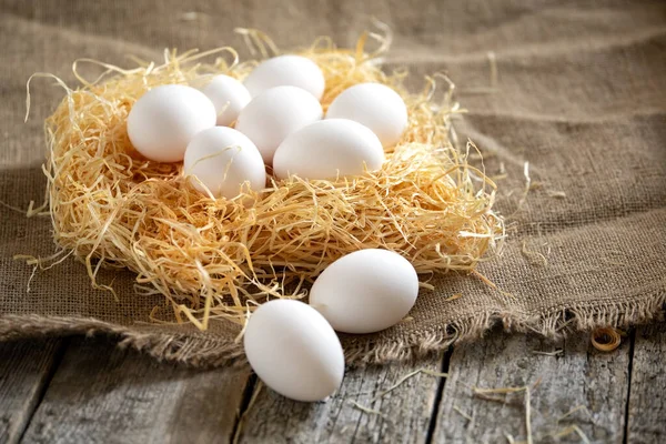 Weiße Hühnereier im Stroh-Nest auf Holzbrettern — Stockfoto