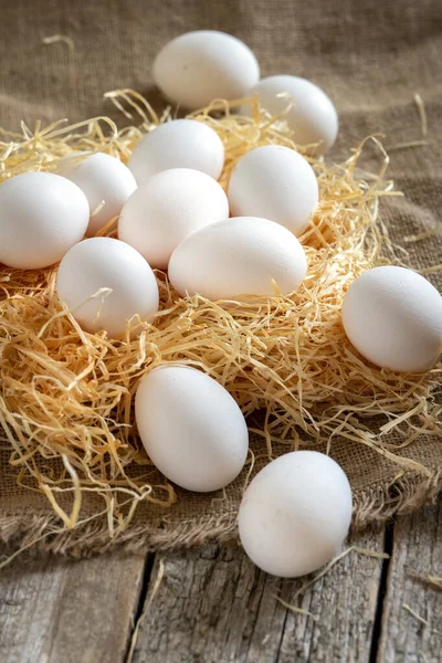 Weiße Hühnereier auf Stroh oder Heu auf Klebetuch und Holzbrettern — Stockfoto