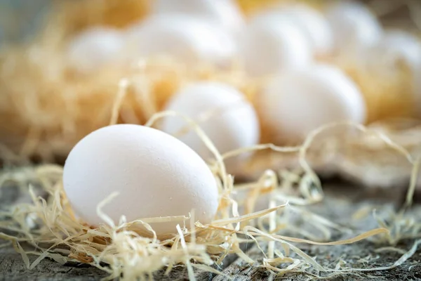 Weiße Hühnereier im Stroh-Nest auf Holzbrettern — Stockfoto