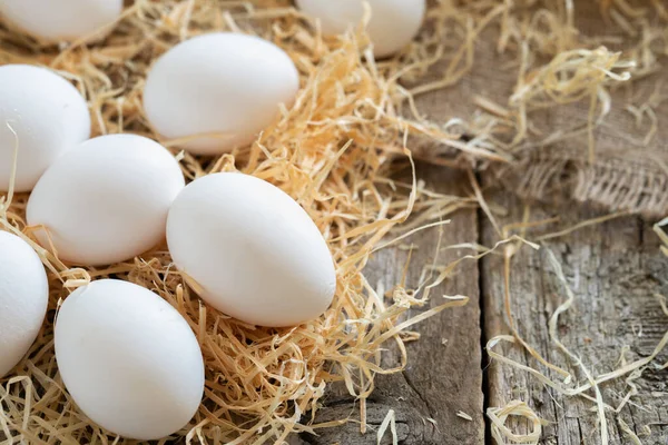 Weiße Hühnereier auf Stroh oder Heu auf Klebetuch und Holzbrettern — Stockfoto