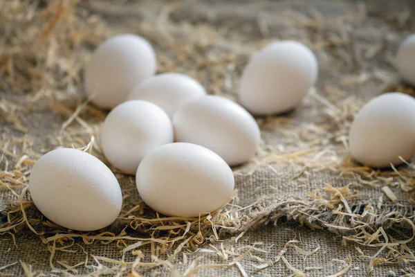 Weiße Hühnereier im Stroh-Nest auf Holzbrettern — Stockfoto