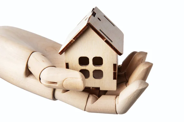 Muñecas de madera mano sostiene una casa de juguete de madera aislada en blanco. Concepto inmobiliario. —  Fotos de Stock