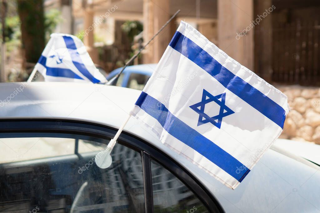 Israel flags waving in the wind attached to the car window outdoors. Celebrating independence day of Israel.