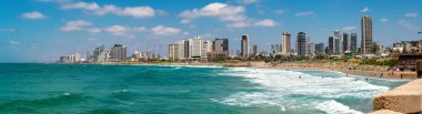 Tel Aviv, Israel-July 15,2022. Panoramic view of Tel Aviv beach with people swimming in the sea and modern buildings on the background in hot summer day