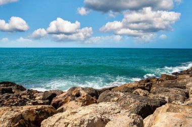 Yaz manzarası kıyılarda kayalar, deniz ve gökyüzü bulutlarla