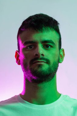 Sakallı, yeşil ve morumsu ışıklarla aydınlatılmış beyaz bir adamın portresi..