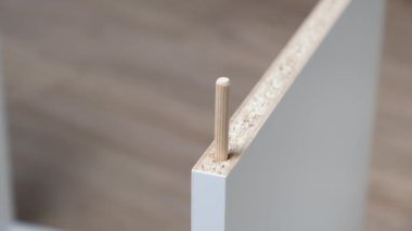 Kafkasyalı adam çekiçle tahta döşemeye tahta döşeme yapıyor. Evdeki mobilyaların montajını kapat