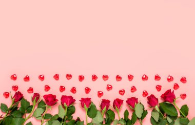 Pink Valentines day background with red roses and hearts in bottom and copy space for text and wishes for birthday, womens, mothers, Valentines day or wedding celebration. Top view, flat lay.