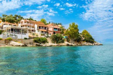 Yunanistan 'ın Korfu adasındaki Kassiopi kasabası. Renkli evleri, lüks villaları ve turkuaz suyu olan engebeli deniz kıyısındaki resim gibi balıkçı köyü. Popüler turizm merkezi.