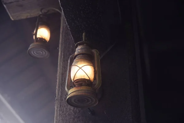 暗い壁に掛けられた中に電球が光るアンティークの2つのランタン — ストック写真