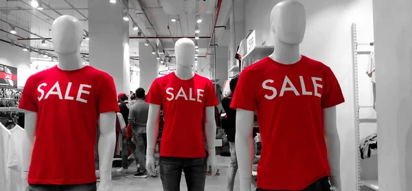 Closeup of Mannequin wearing Red T-shirt written Sale displayed in the front of a Clothing Showroom.