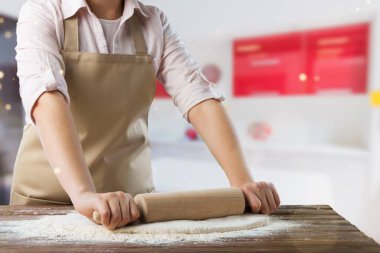 Önlük giymiş olgun bir kadın ekmek pişiriyor ya da evdeki sıcak mutfakta turta yapıyor..