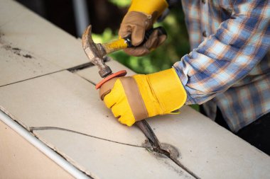 Eldivenli bir işçi merdivenlerin seramik fayanslarını söker.