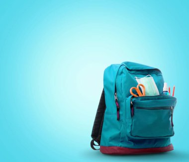 Masasında farklı renkli kırtasiye ürünleri olan okul çantası.