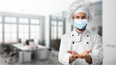 Şef şapkalı, koruyucu maskeli aşçı.