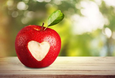 Masanın üzerine kalp işareti kazınmış elma.