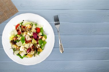 Taze sebzeli salata ve ahşap arka planda fındık.