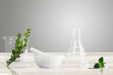 Tahta masadaki yeşil yapraklı cam eşyalar.